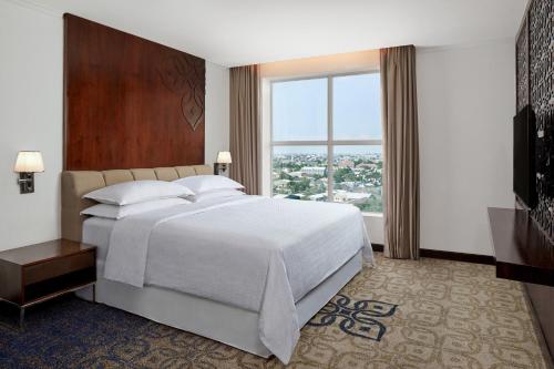 a bedroom with a large bed and a large window at Four Points by Sheraton Makassar in Makassar