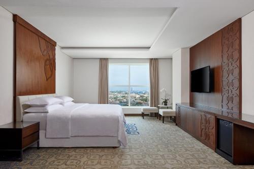 a hotel room with a bed and a flat screen tv at Four Points by Sheraton Makassar in Makassar