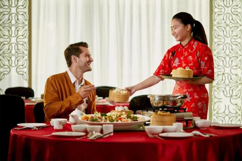 a man and a woman standing over a table with food at Four Points by Sheraton Makassar in Makassar