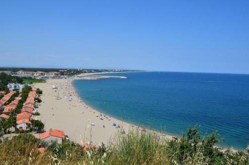a view of a beach with people and the ocean at Appartement avec piscine et jacuzzi à 50mètres de la plage et 5min de l'allée des Pins in Argelès-sur-Mer