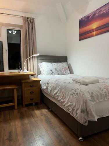 a bedroom with a bed and a desk and a window at House in city centre with free parking in Cambridge