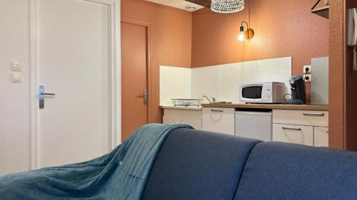 une cuisine avec un canapé bleu et un four micro-ondes dans l'établissement Charlie Brown, à Nevers