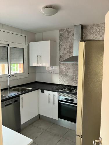 a kitchen with white cabinets and a black stove top oven at Descanso del GUERRERO in San Miguel de Fluviá