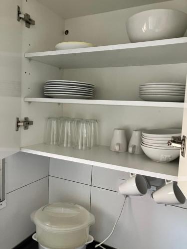 a kitchen with white shelves with dishes and a toilet at Descanso del GUERRERO in San Miguel de Fluviá
