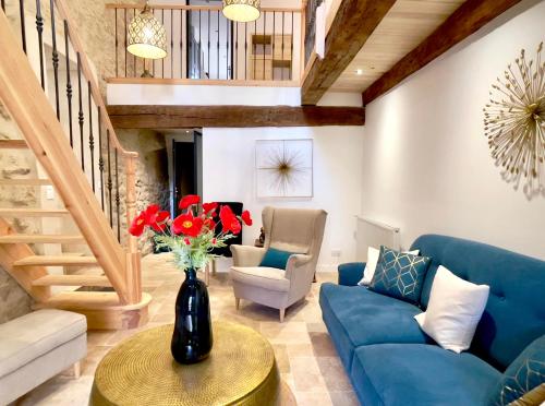 a living room with a blue couch and a vase with red flowers at Villa Eleonore - Chic Central Retreat Heated Pool in Monségur