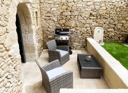 a patio with a grill and chairs and a table at Villa Eleonore - Chic Central Retreat Heated Pool in Monségur