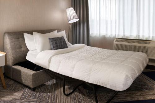 a bedroom with a large white bed and a chair at Four Points by Sheraton Windsor Downtown in Windsor