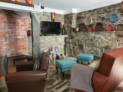 a living room with a couch and chairs and a tv at Casa Iris Cunqueiros in Sobreira Formosa