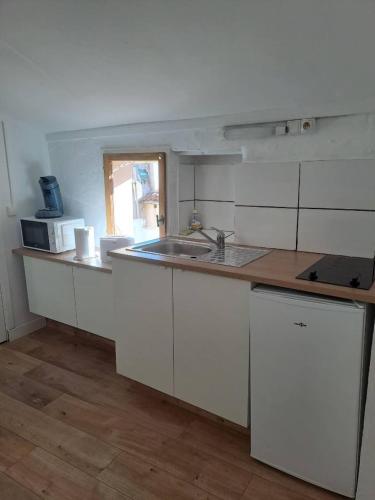 une cuisine avec des armoires blanches, un évier et une fenêtre dans l'établissement Budgetbnb 195B, studette Porte d 'Italie popular street, à Toulon