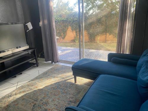 a living room with a blue couch and a television at Departamento con vista al jardín in Tijuana