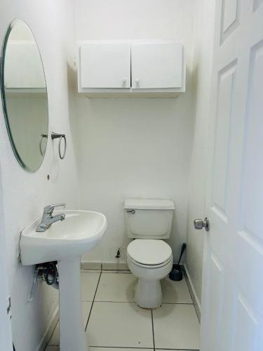 a bathroom with a toilet and a sink and a mirror at Departamento con vista al jardín in Tijuana