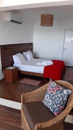 a bedroom with a bed and a chair with a pillow at Pousada Recanto Ha Mar in Maceió