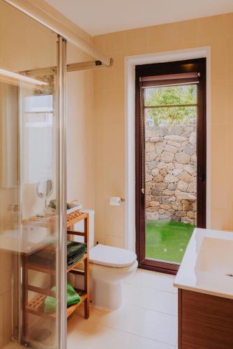 a bathroom with a shower and a toilet and a window at Villa Alba Deluxe & Spa Pool in Playa Blanca