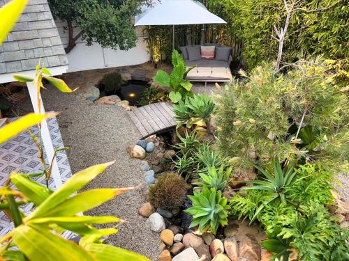 a garden with a bench and plants and an umbrella at Channel Islands Beach Retreat in Oxnard