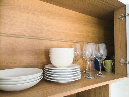 a cabinet with plates and wine glasses on a shelf at Apartamento com terraço no Rocio Pequeno in São Francisco do Sul