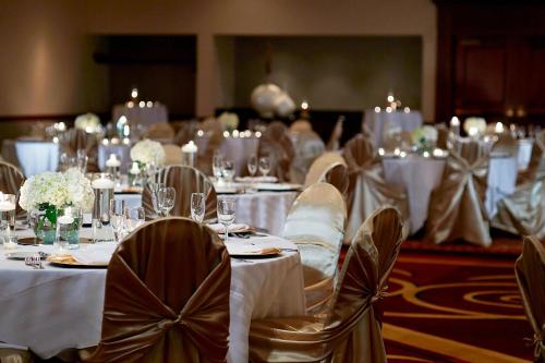 a group of tables with white table cloths and chairs at Marriott Cincinnati Airport in Hebron