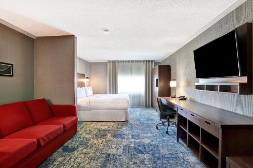 a hotel room with a bed and a red couch at Four Points by Sheraton Toronto Mississauga in Mississauga