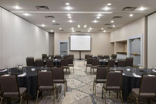 a conference room with tables and chairs and a white screen at Marriott Cincinnati North in West Chester