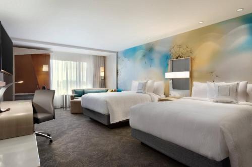 a hotel room with two beds and a desk at Courtyard by Marriott Toronto Mississauga/West in Mississauga