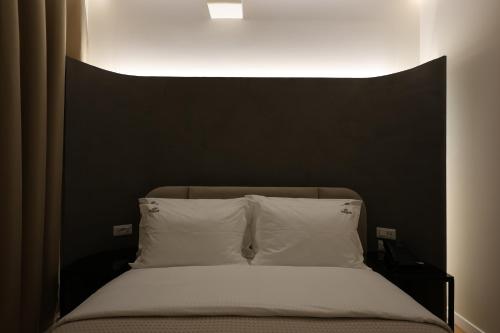 a bed with a black headboard and white pillows at Beratinus1 in Berat