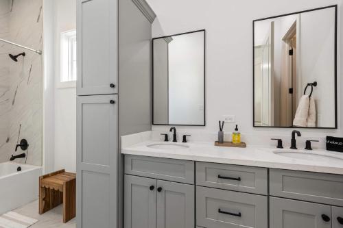 un baño con dos lavabos y dos espejos en New cottage near Sports Complex with King Beds, en Youngsville