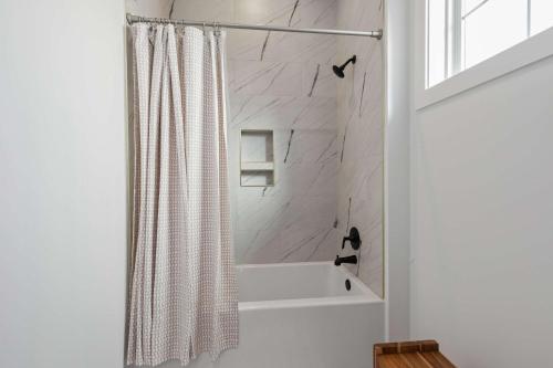 a white bathroom with a shower curtain and a tub at New cottage near Sports Complex with King Beds in Youngsville