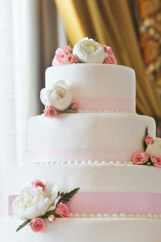 a three tiered wedding cake with pink and white flowers at Hotel Grande Bretagne, a Luxury Collection Hotel, Athens in Athens