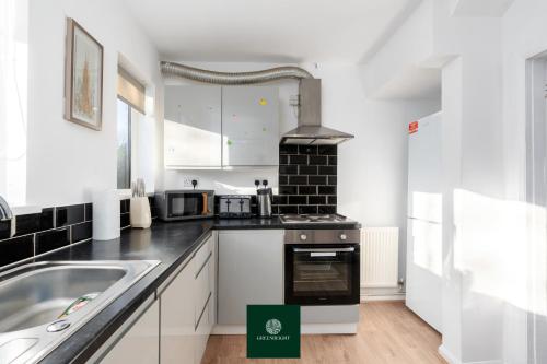 a kitchen with white cabinets and a sink at 3 Bed House with King Size bed near Uni and QMC in Nottingham