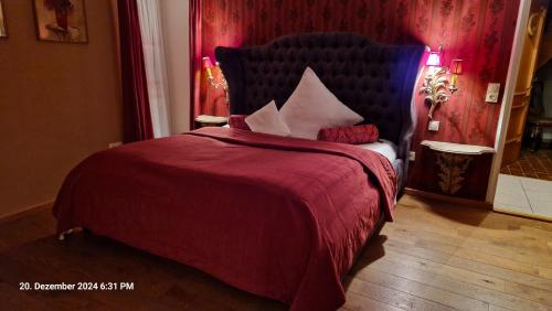 a bedroom with a large bed with a red blanket at Alte Pfarrey in Neuleiningen