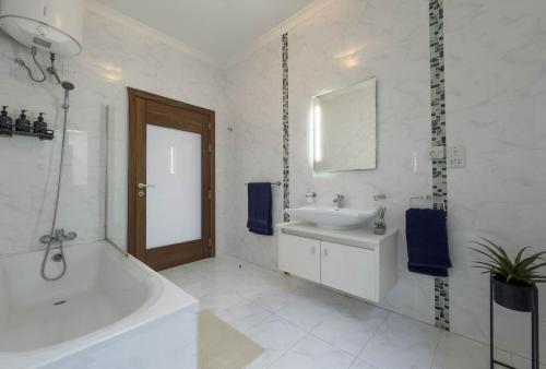 a white bathroom with a tub and a sink at Jacuzzi Terrace Getaway with Valletta Views in Sliema