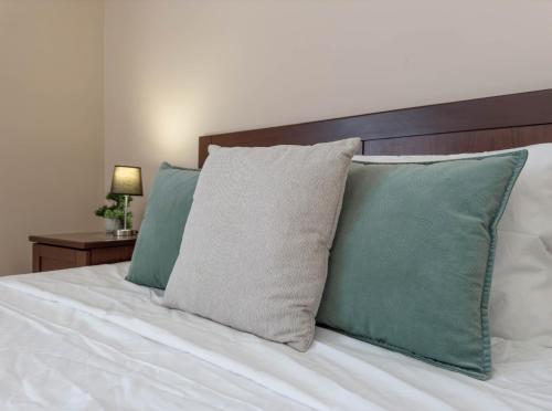 a bed with green pillows and a wooden headboard at Jacuzzi Terrace Getaway with Valletta Views in Sliema