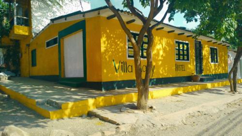 a yellow building with a tree in front of it at Villa Mary Hostel in Taganga