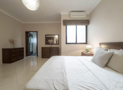 a bedroom with a large white bed and a mirror at Jacuzzi Terrace Getaway with Valletta Views in Sliema