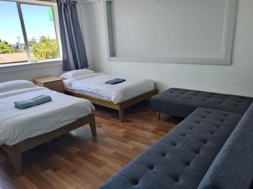 a room with two beds and a bench and a window at 5 Beds including 1 Double Bed, 2 single Beds, 2 Double Sofa Beds, Suite 4, 37 Totara Avenue, New Lynn in Auckland
