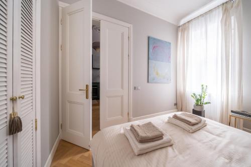 a white bedroom with a bed with two towels on it at Luxury Design Apartment Riga in Rīga