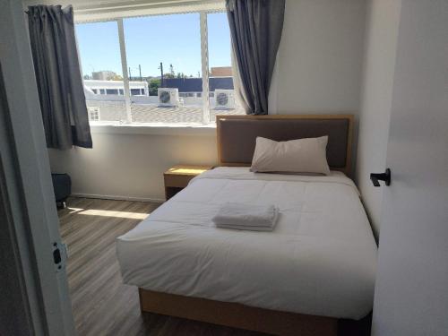 a bed in a small room with a window at 9 Beds including 3 Double Beds, 4 Single Beds, 2 Sofa Bed, Suite 1, 37 Totara Avenue, New Lynn in Auckland