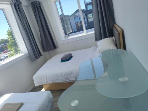 a small bedroom with a bed and a glass table at 9 Beds including 3 Double Beds, 4 Single Beds, 2 Sofa Bed, Suite 1, 37 Totara Avenue, New Lynn in Auckland