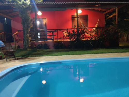 a swimming pool in front of a house with a red wall at Casa alto da vista in Tibau do Sul