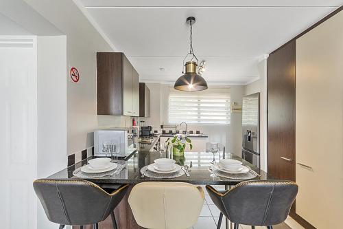 a kitchen with a dining table with chairs and a kitchen with at Modern 2 Bed Apartment-Self Check In-Next to Dainfern Square Shopping Centre in Sandton
