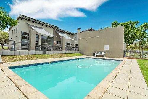 a swimming pool in front of a house at Modern 2 Bed Apartment-Self Check In-Next to Dainfern Square Shopping Centre in Sandton