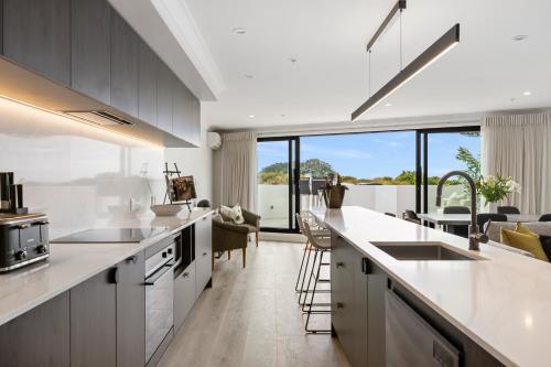a kitchen with white countertops and a living room at Belle Mer Beachfront Apartments in Mount Maunganui