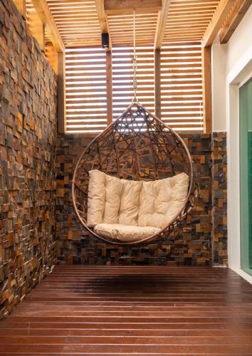 a hanging chair in a room with a brick wall at Pousada Cristalmar in Bombinhas