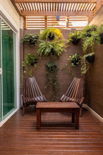 two benches on a porch with plants on a wall at Pousada Cristalmar in Bombinhas