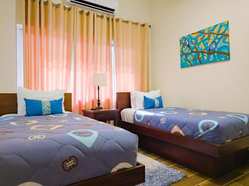 a bedroom with two beds and a window at Louis' Apartments in Placencia Village