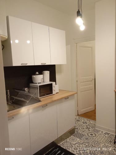 une cuisine avec des placards blancs et un four micro-ondes sur un comptoir dans l'établissement Beau studio propre, à Colombes