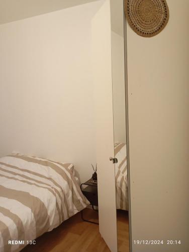 1 dormitorio con cama y puerta blanca en Beau studio propre, en Colombes