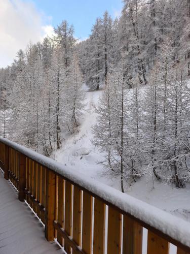 a balcony with snow covered trees and a bridge at Duplex 6 personne au pied des pistes in Allos
