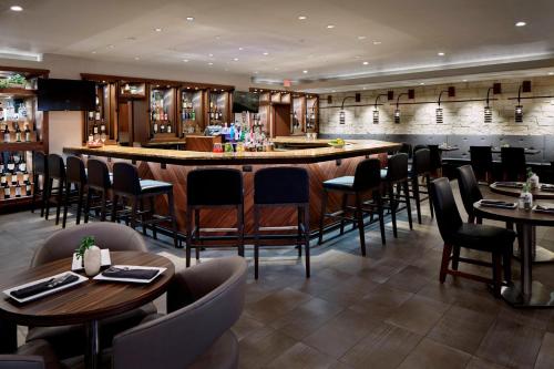 a restaurant with tables and chairs and a bar at Marriott DFW Airport South in Fort Worth