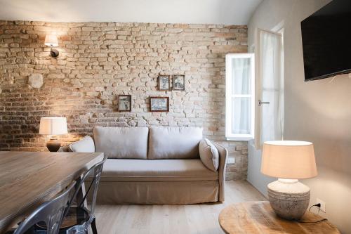 a living room with a couch and a brick wall at Le Antiche Mura 2 in Guastalla