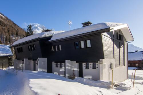 une maison noire avec de la neige devant elle dans l'établissement Les Soldanelles Happy Rentals, à Le Tour